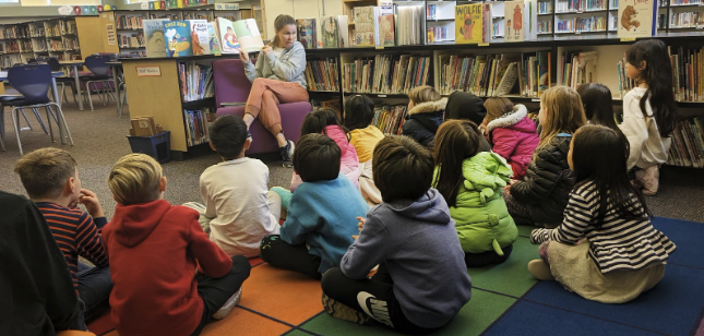 Librarian reading a book to students